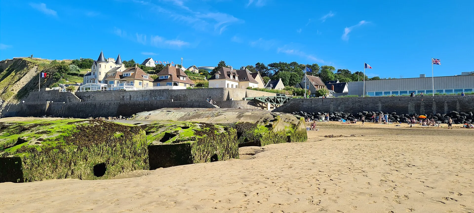 Plage d'Arromanches en été, baigneurs et promeneurs devant le front de mer et les villas